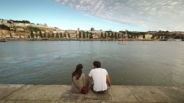傍晚时分，一对夫妇坐在葡萄牙波尔图的杜罗河畔视频下载
