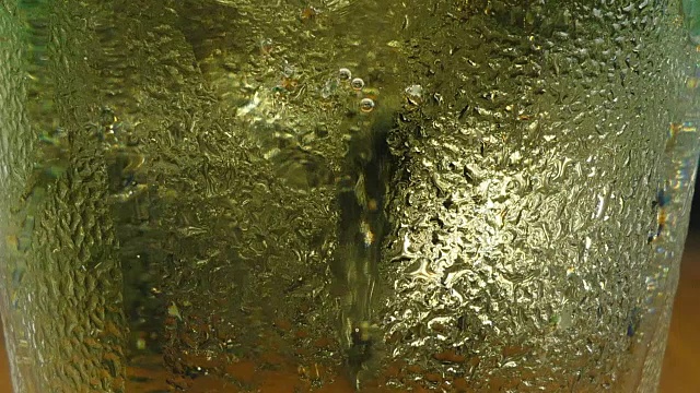 许多气泡和泡沫从寒冷的黄色啤酒缓慢移动在一个透明的玻璃，微距特写视频下载
