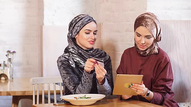 两个穆斯林女商人在咖啡馆里开发平板电脑视频素材