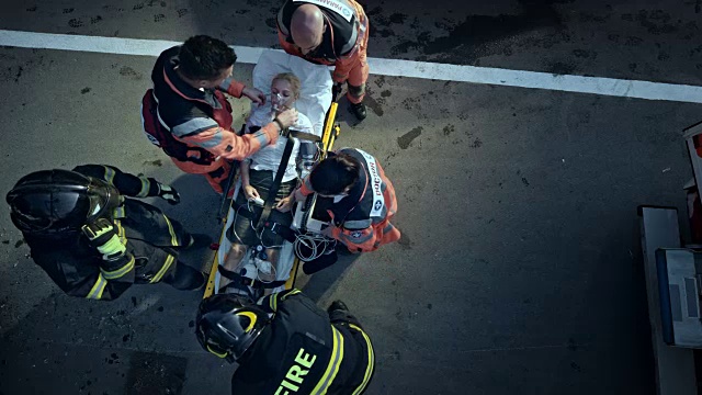 在消防队员的帮助下，CS医护人员将受伤的妇女放在担架上准备运送视频下载