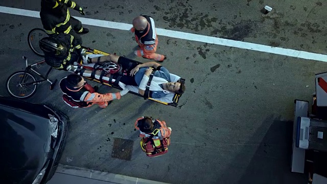 CS消防员正在帮助医护人员把受伤的骑自行车的人抬上救护车视频下载