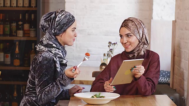 两个穆斯林女商人在咖啡馆里开发平板电脑视频素材