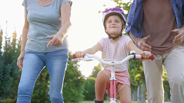 爷爷奶奶帮助孙女第一次骑自行车，并为她欢呼视频素材