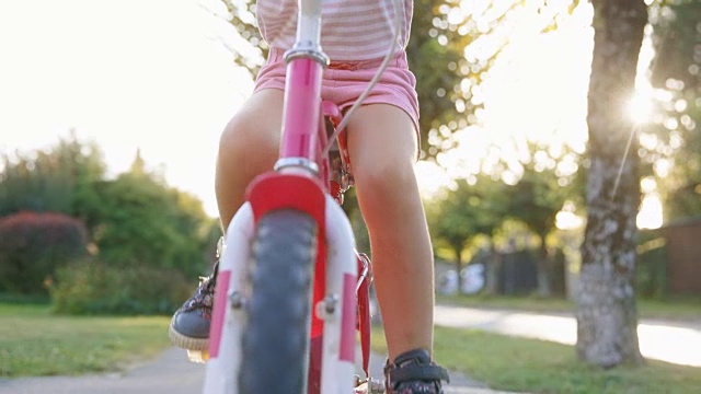 SLO MO一个孩子的腿骑着自行车在一个社区的阳光视频素材
