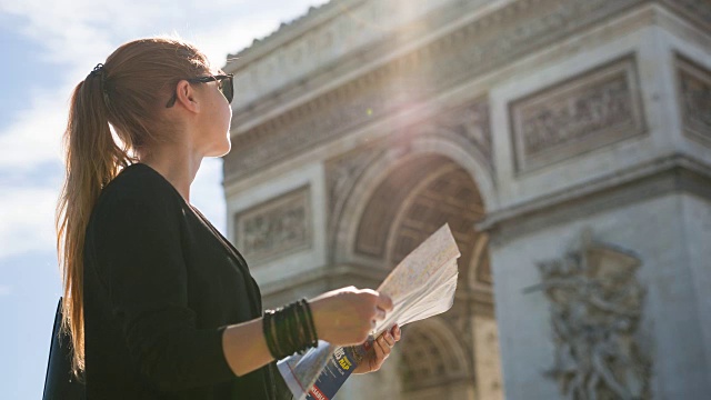 一个女人站在凯旋门前看巴黎地图视频素材