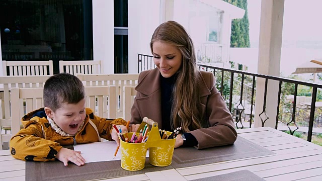 母亲和小儿子在桌子旁画画视频素材