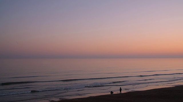 黄昏时分，人们站在布莱顿海滩的海岸线上。视频素材