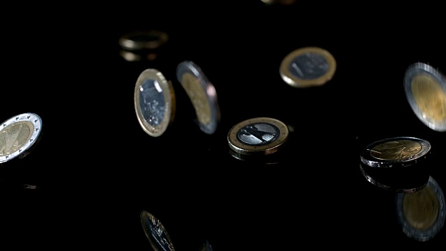 欧元硬币掉落在反光表面的慢动作镜头。视频素材