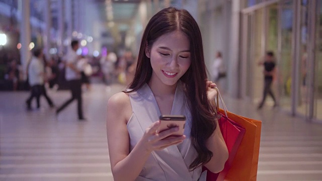一名女子在購物中心使用智能手機。視頻下載
