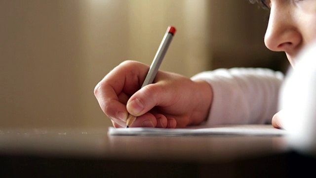孩子用铅笔练习在书上写字。视频下载