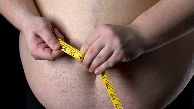 胖人用黄色卷尺测量自己的腹部，减肥控制，饮食效果好视频下载