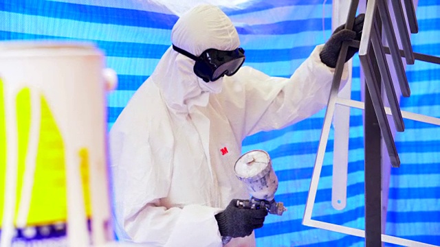 慢镜头:一个戴着防护面具、穿着工作服的成年人正在粉刷家具视频素材