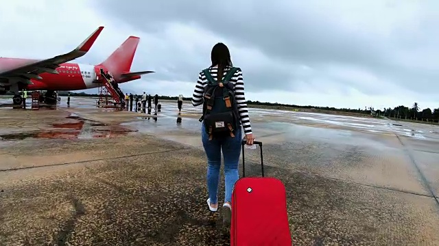 带着红色行李走向飞机的女性旅客视频素材