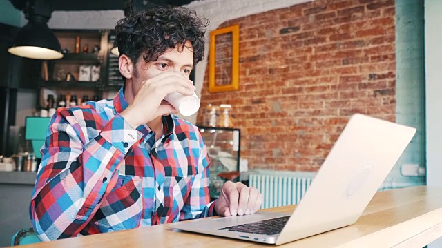 一个年轻人在咖啡馆用笔记本电脑。视频素材