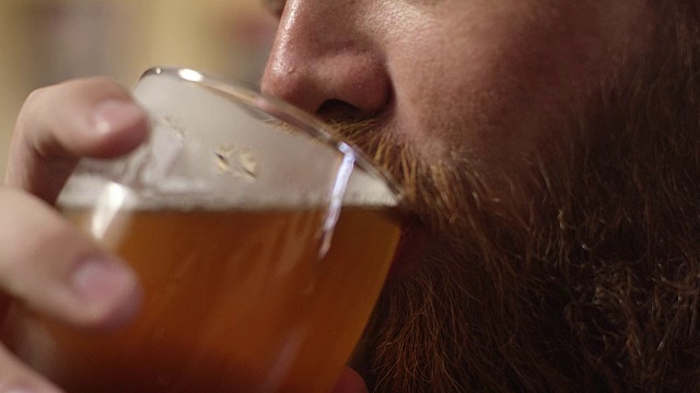 一个年轻的红胡子白人男子在喝啤酒视频下载