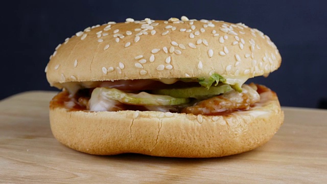4k拍摄，新鲜可口的汉堡，撒上芝麻在黑色背景上旋转视频下载