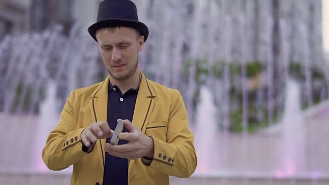 魔术师戴着帽子，穿着黄色夹克，熟练地移动手中的扑克牌视频下载