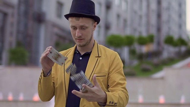 穿着黄色夹克和帽子的魔术师玩扑克牌玩得很开心视频下载