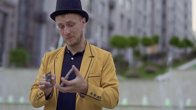 戴着帽子，穿着黄色夹克，手里拿着扑克牌的魔术师视频下载