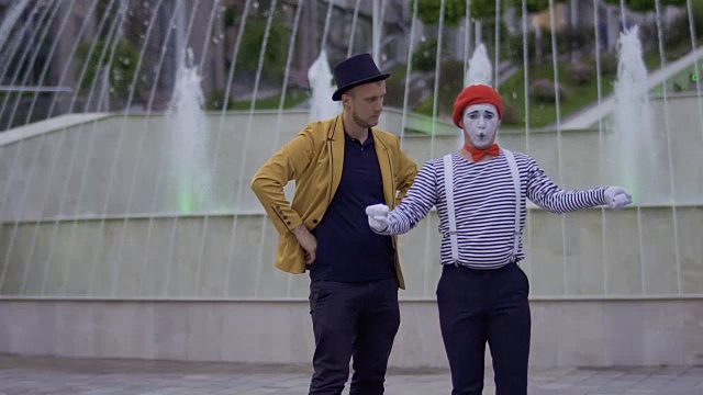 魔术师和哑剧演员站在发光的喷泉背景下玩得很开心视频下载
