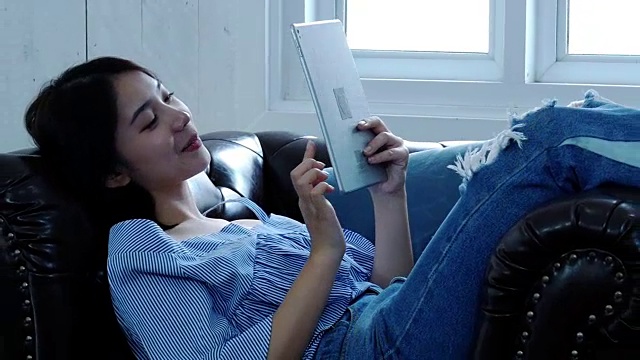 年轻女子躺在沙发上使用笔记本电脑视频素材