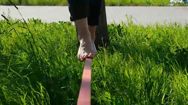 女人的腿在公园里走着。近距离的女脚丫在松弛的绳索上保持平衡视频下载