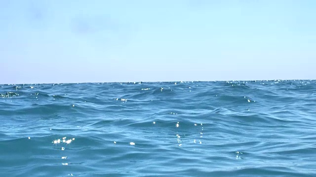 海浪在蓝色的海里缓慢移动。镜头在海洋中摆动，然后沉入水中。视频下载