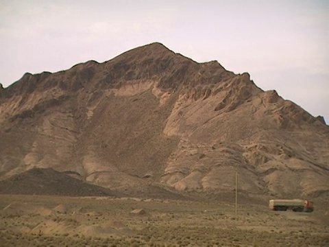 伊朗庫姆城外，稀稀疏疏的卡車行駛在荒蕪的沙漠路上，崎嶇的山區視頻素材