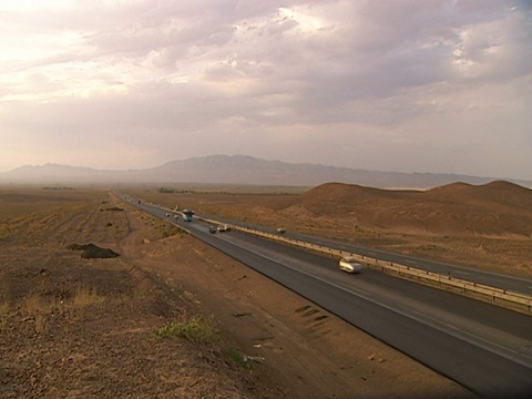PAN在高速公路系統上行駛的車輛穿過廣闊的沙漠和遙遠的地平線上的山脈/伊朗視頻素材