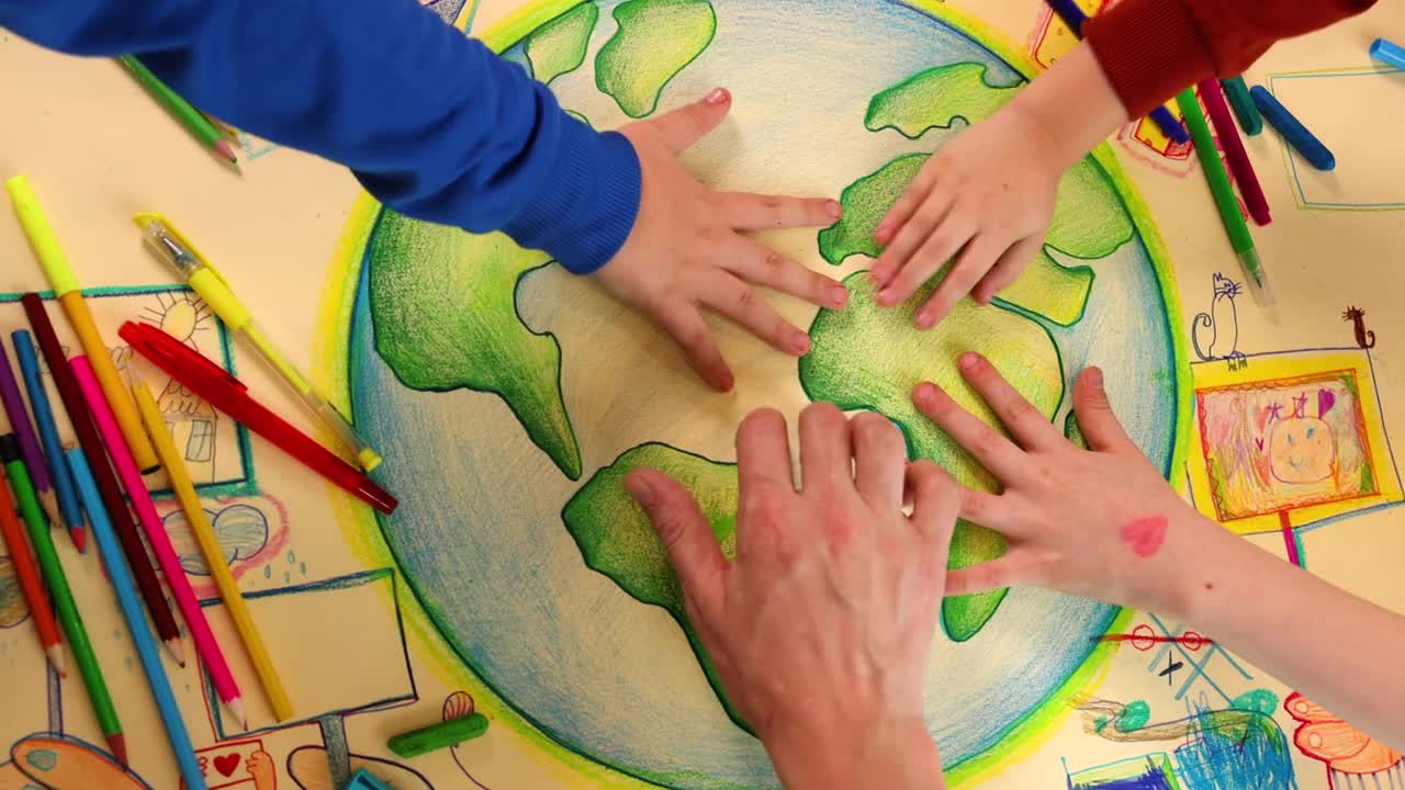 一组孩子和老师的手紧握在他们创作的关于可持续发展的艺术作品上的镜头视频下载