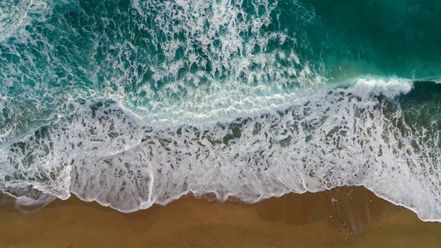 海浪或海浪拍岸。泡沫状的海浪翻滚着涌向沙滩。空中拍摄，4K视频购买