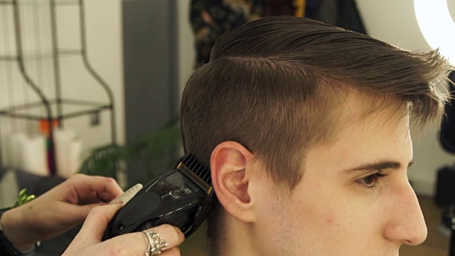 理发师在美发厅用电动剃须刀为男士理发视频