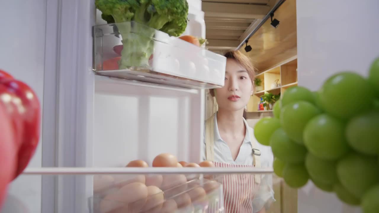 青年女人开冰箱拿食品视频素材