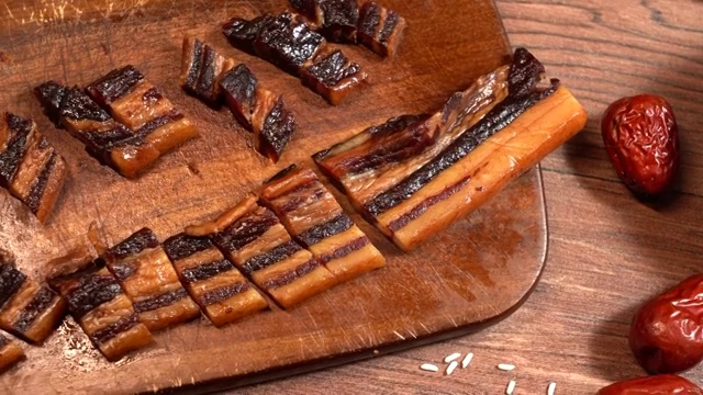 红褐色木板桌面上碗里的粽子和旁边的原料视频下载