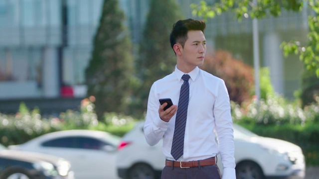 年轻商务男士在街上使用手机视频下载
