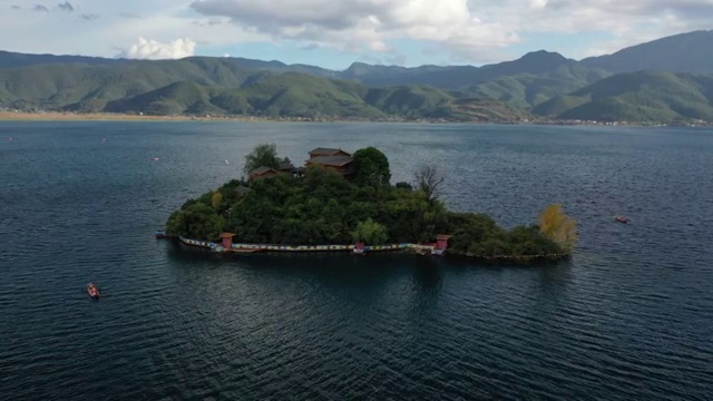 空中俯瞰泸沽湖王妃岛四周船只来来往往的景观视频素材