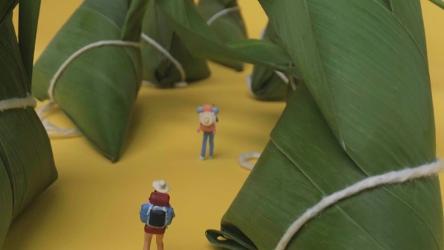 背包小人穿过放置在黄色背景上的一排粽子视频素材