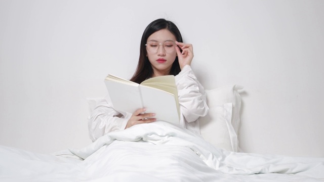 坐在床上看书的亚洲美女视频素材