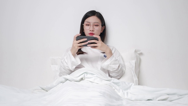 坐在床上玩手机的亚洲美女视频素材