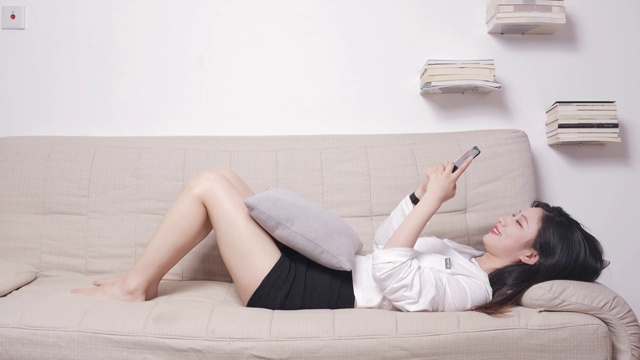 躺在沙发上玩手机的亚洲美女视频素材