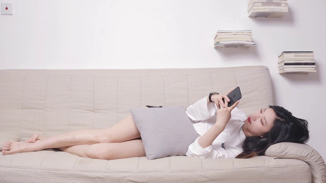 躺在沙发上玩手机的亚洲美女视频素材