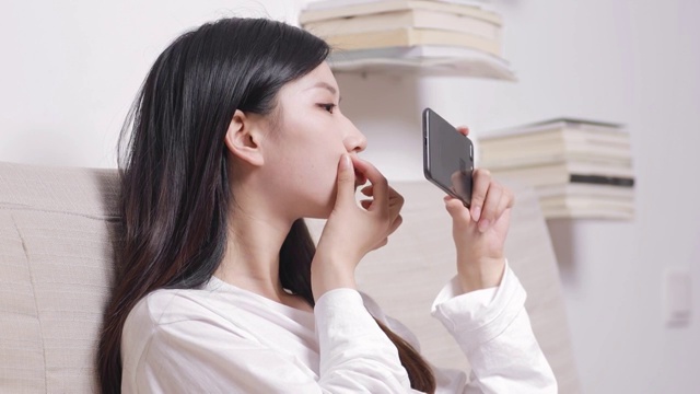亚洲美女对着手机屏幕化妆视频素材