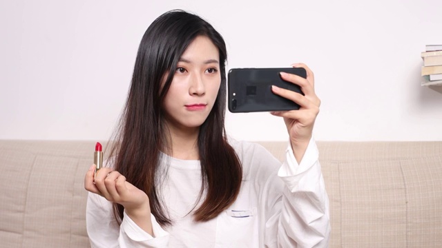 亚洲美女对着手机屏幕化妆视频素材