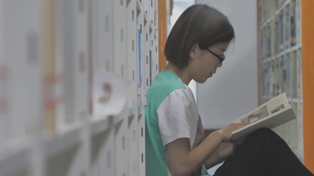 亚洲年轻女子在图书馆看书翻书视频购买
