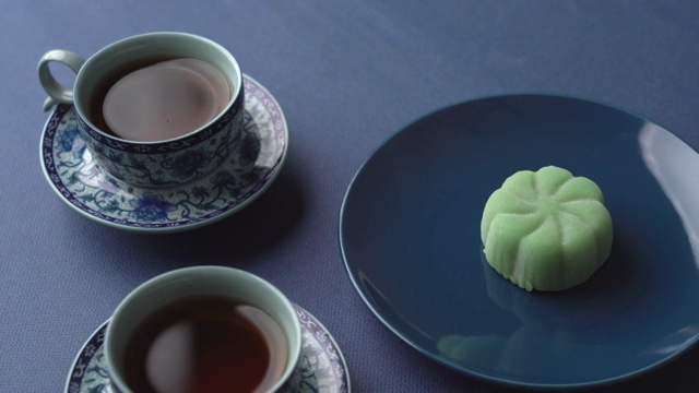 深蓝色背景上的茶杯和绿色的水果月饼视频素材
