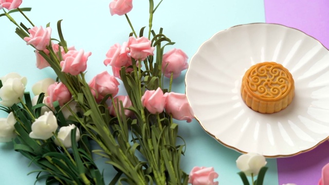 彩色背景上的花朵和托盘中央的小月饼视频素材