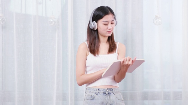 可爱的中国女孩，正在带着耳机看书视频素材
