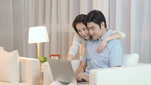 快乐的年轻情侣在客厅使用笔记本电脑视频下载