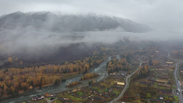 新疆阿勒泰布尔津县喀纳斯景区禾木乡村庄河流与烟雾秋季航拍视频素材