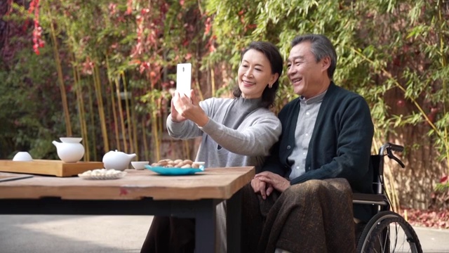 老年夫妇在庭院使用手机视频购买